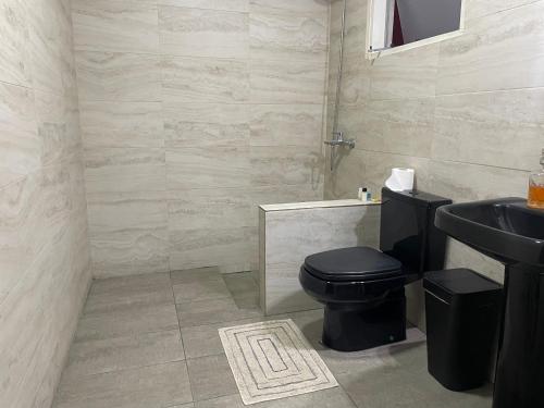 a bathroom with a black toilet and a sink at Habitación a minutos del centro de Asunción in Asuncion