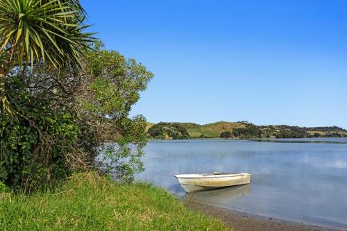 a small boat sitting on the shore of a lake at Sandbach - Ohiwa Harbour in Waiotahi