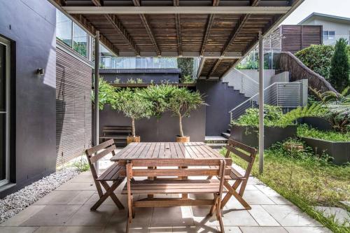 a patio with a wooden table and two benches at 11 East Gosford Luxury Waterfront House with Private Wharf in Gosford