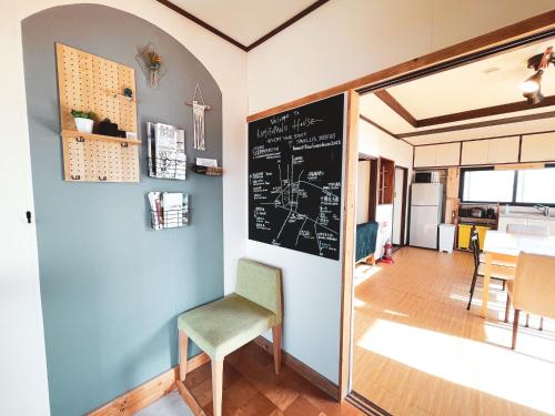 una habitación con una pizarra en la pared y una silla en Kamifurano House, en Kami-furano