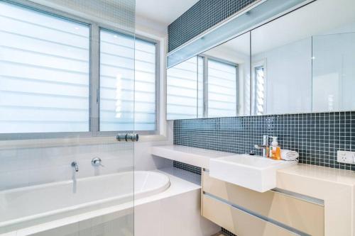 La salle de bains est pourvue d'une baignoire blanche et d'un lavabo. dans l'établissement 11 East Gosford Luxury Waterfront House with Private Wharf, à Gosford
