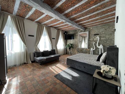een slaapkamer met een bed, een bank en ramen bij Suite Royale Hotel Ferme Du Château Fontaine in Fontaine-lʼÉvêque