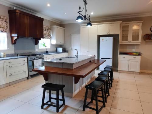 a kitchen with white cabinets and a large island with stools at Verdant Valley Lodge in Albert Falls