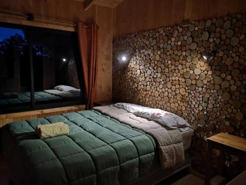 a bedroom with a bed with a wall of logs at Hostel Calafquen Coñaripe in Coñaripe