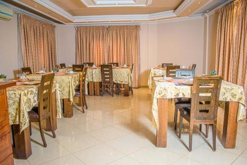 uma sala de jantar com mesas, cadeiras e cortinas em Hotel Murex em Brazavile