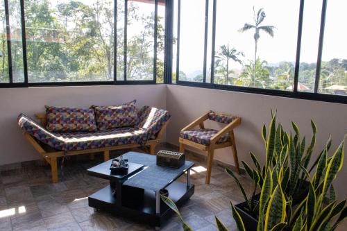 une chambre avec deux chaises, une table et des fenêtres dans l'établissement Bio-Hotel entre café, bosque y montañas, à Cachipay