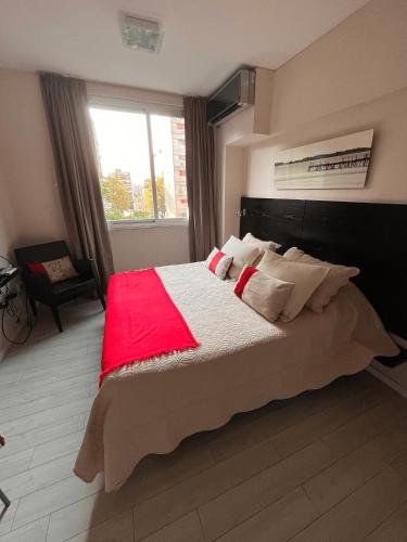 a bedroom with a large bed with a red blanket at Monoambiente Frente Al Hospital Italiano in Buenos Aires