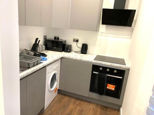 a kitchen with a washing machine and a microwave at Buckinghamshire Elegant Studio in Buckinghamshire