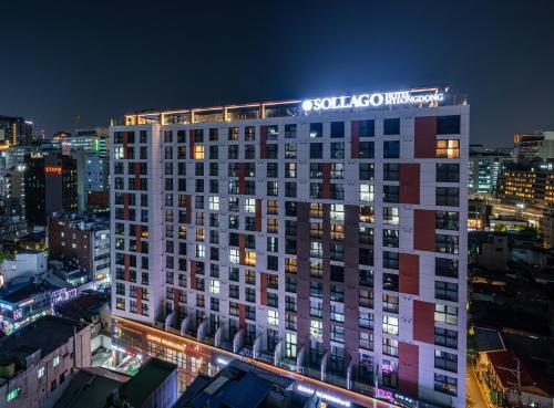a building with a sign on top of it at night at Sollago Myeongdong Hotel & Residence in Seoul