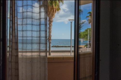 een raam met uitzicht op de oceaan en een palmboom bij B&B Benvenuti al Sud in Crotone