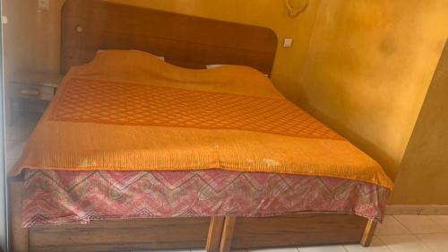 a bed with an orange comforter in a room at Ker mame fatou in Sali Nianiaral