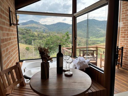 a table with a bottle of wine and two glasses at Pousada Ho'oponopono Chalets & Wine in Sapucaí-Mirim