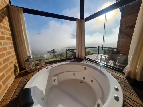 a bath tub in a room with a large window at Pousada Ho'oponopono Chalets & Wine in Sapucaí-Mirim