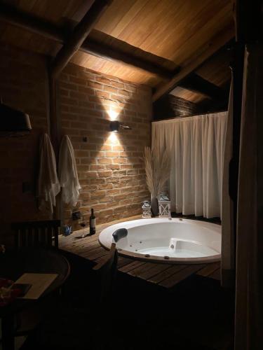 a large bath tub in a room with a brick wall at Pousada Ho'oponopono Chalets & Wine in Sapucaí-Mirim
