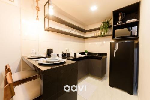 a kitchen with a black refrigerator and a counter at Gaudium Apart-hotel por Quarto à Vista in João Pessoa