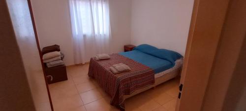 a small bedroom with a bed with a blue blanket at Departamento Estrada in Santa Rosa