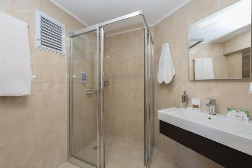 a bathroom with a glass shower and a sink at Asdem Park Otel in Kemer