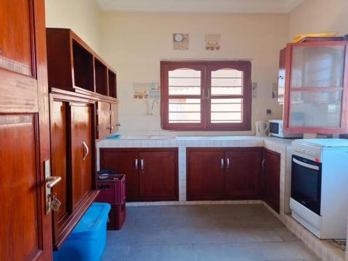 een keuken met houten kasten en een raam bij Villa privée avec garden à bord de plage in Cotonou