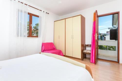 a bedroom with a bed and a pink chair at Apartment Seget Vranjica 1038b in Seget Vranjica