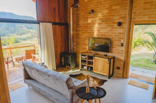 een woonkamer met een bank en een televisie bij Pousada Ho'oponopono Chalets & Wine in Sapucaí-Mirim