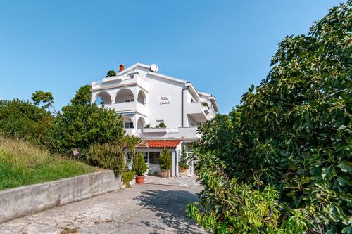 a large white building with trees in front of it at Apartments with a parking space Banjol, Rab - 5022 in Rab