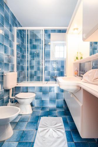 a blue tiled bathroom with a toilet and a sink at Apartments with parking space Banjol, Rab - 5022 in Rab