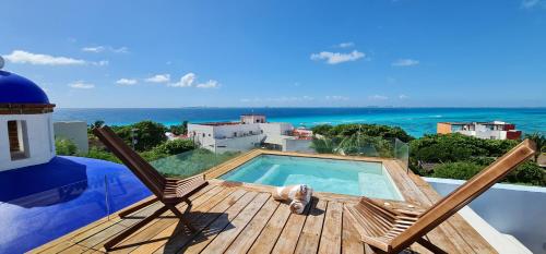 a deck with two chairs and a swimming pool at CASA REYES Stunning Rooftop Oceanview in Isla Mujeres