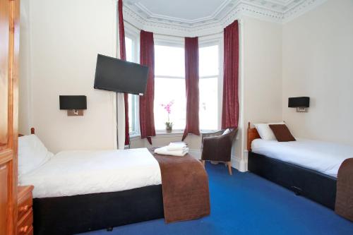 Habitación de hotel con 2 camas y TV de pantalla plana. en CitiHouse Aberdeen West End en Aberdeen
