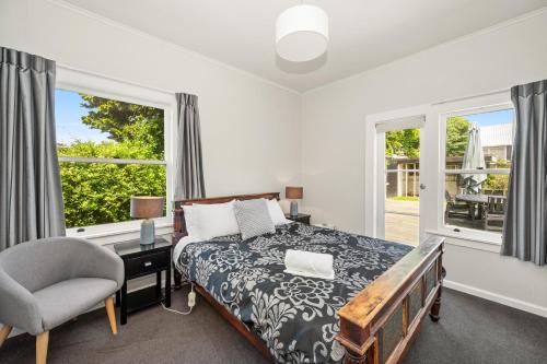 - une chambre avec un lit, une chaise et des fenêtres dans l'établissement Springfield Rise Lodge - Rotorua Holiday Home, à Rotorua
