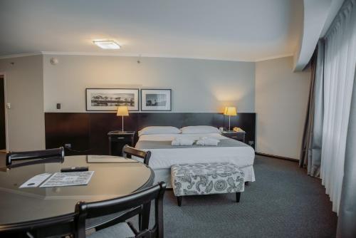 a hotel room with two beds and a desk at Plaza Real Suites Hotel in Rosario