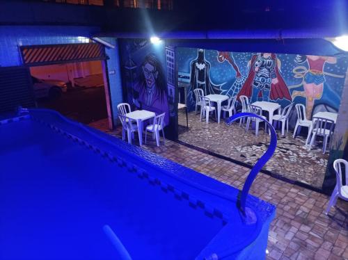 a wall with a mural with tables and chairs at night at Casa de piscina Guarujá in Guarujá