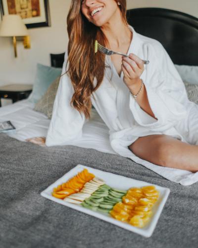 a woman sitting on a bed with a plate of food at Plaza Real Suites Hotel in Rosario
