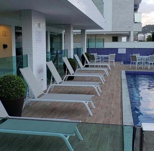 a row of lounge chairs next to a swimming pool at Apartamento na Praia de Palmas com garagem in Governador Celso Ramos