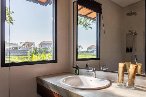 uma casa de banho com um lavatório e 2 janelas em Paripadi Studio Canggu em Canggu