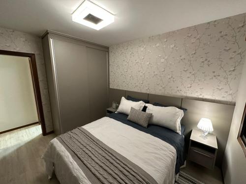 ein Schlafzimmer mit einem Bett und einer Wand mit Blumen in der Unterkunft Apto super luxo beira mar Capão da Canoa in Capão da Canoa