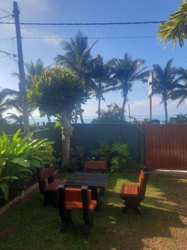 a picnic table and benches in a yard with palm trees at White Surfing Beach Resort in Unawatuna