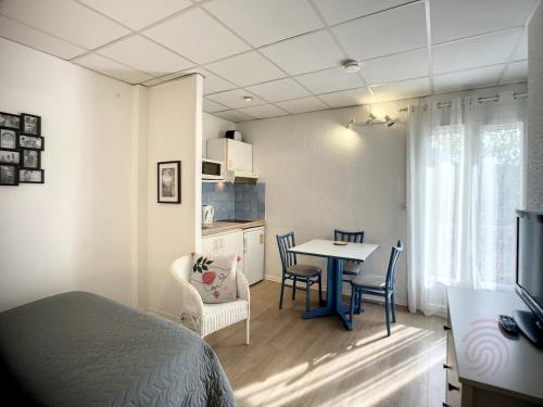 une chambre avec un lit, une table et des chaises dans l'établissement Studio lumineux avec balcon à 50m des Thermes - Animaux acceptés, Wifi, options confort disponibles - FR-1-451-176, à Lamalou-les-Bains
