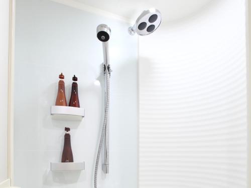 a shower with a shower head and bottles on the wall at Tokyu Stay Kamata - Tokyo Haneda in Tokyo