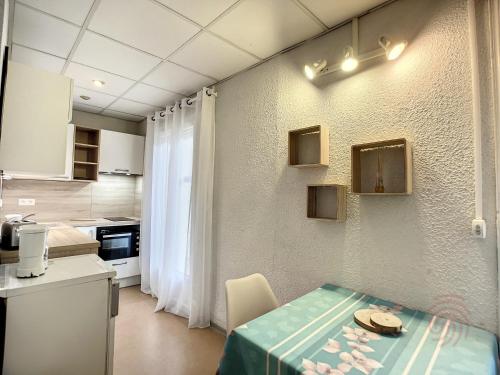 une petite cuisine avec une table et une cuisine gmaxwell gmaxwell gmaxwell dans l'établissement Séjour Idéal à Lamalou: Studio 28 m², Balcon, Proche Thermes, Animaux Acceptés, Wifi Inclus - FR-1-451-182, à Lamalou-les-Bains