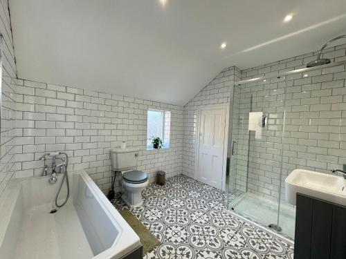 a bathroom with a tub and a toilet and a sink at Longsands Apartment, Tynemouth Luxury Coastal Retreat in Tynemouth