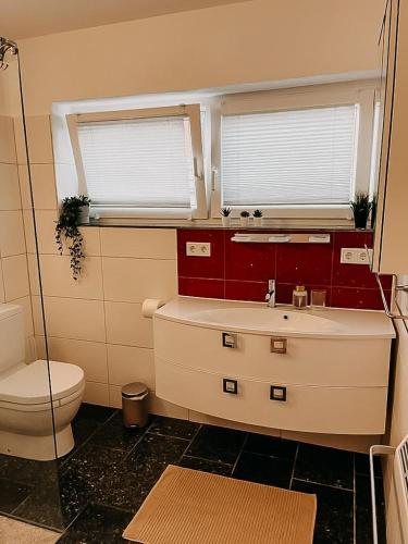 a bathroom with a toilet and a sink and two windows at Wohnen im 3 Ländereck! Essen, Mülheim, Oberhausen. BSEG in Essen