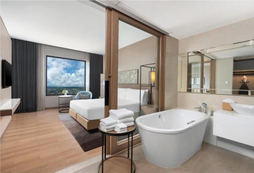 a bathroom with a tub and a bedroom with a bed at Holiday Inn & Suites Rayong City Centre, an IHG Hotel in Rayong