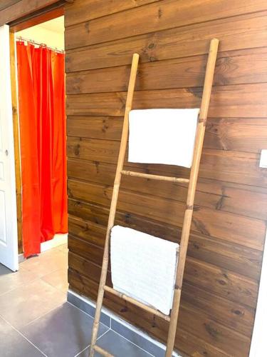 a ladder leaning against a wooden wall with two white chairs at Maison Marouka sur la plage du Diamant in Le Diamant