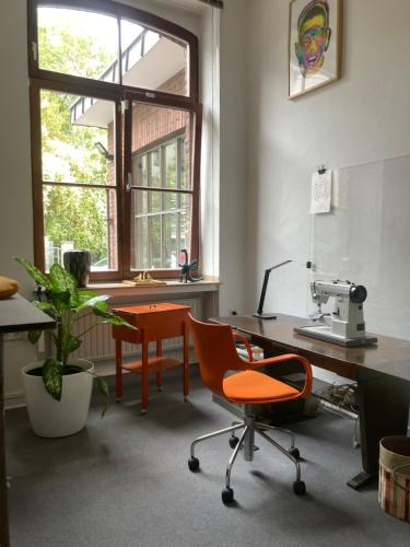 an office with orange chairs and a desk and a microscope at Art Loft in Cologne