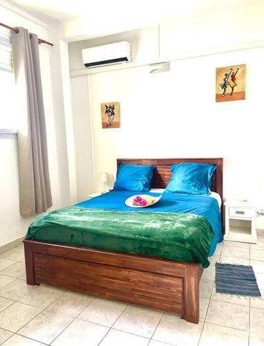 a bedroom with a bed with a blue comforter at Maison Marouka sur la plage du Diamant in Le Diamant