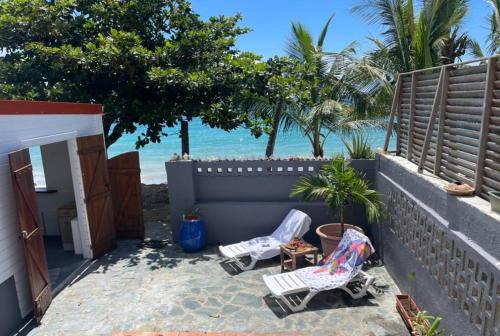 a patio with two lawn chairs and the beach at Maison Marouka sur la plage du Diamant in Le Diamant