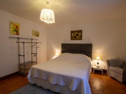 um quarto com uma cama branca e um lustre em Appartement Biron, 2 pièces, 2 personnes - FR-1-616-122 em Biron