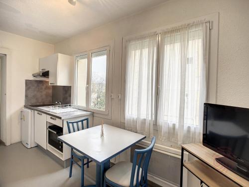 une cuisine avec une table et des chaises et une télévision dans l'établissement Appartement F2 avec Véranda, Wifi et Animaux Acceptés Proche Thermes et Parc - Lamalou-les-Bains - FR-1-451-171, à Lamalou-les-Bains