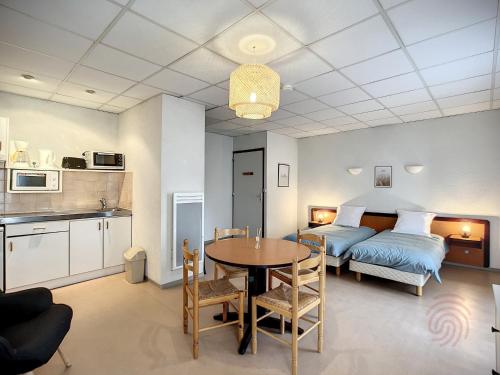 une chambre avec un lit et une table dans une pièce dans l'établissement Appartement au cœur de Lamalou-les-Bains, proche thermes et centre-ville, avec balcons et Wifi. - FR-1-451-172, à Lamalou-les-Bains