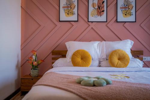 a bedroom with a pink wall and a bed with yellow pillows at Stay.vie Hotel in Surabaya